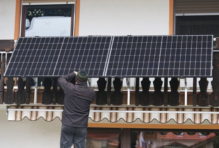 a man assembles a balcony power plant to generate electricity
